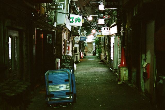 A narrow Shinjuku alley at night, lit by small signs